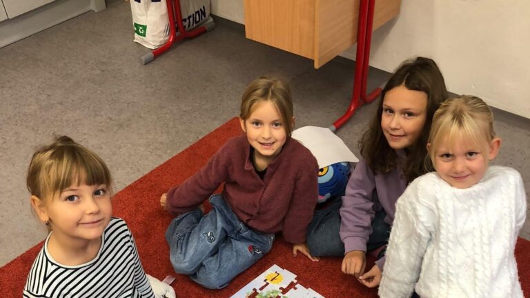 Žákyně skládají stromové puzzle na koberci