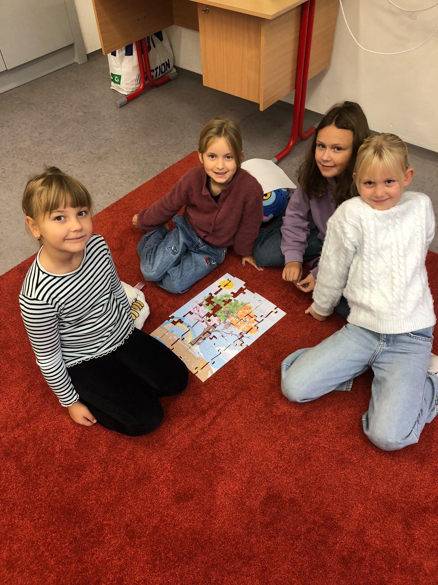 Žákyně skládají stromové puzzle na koberci
